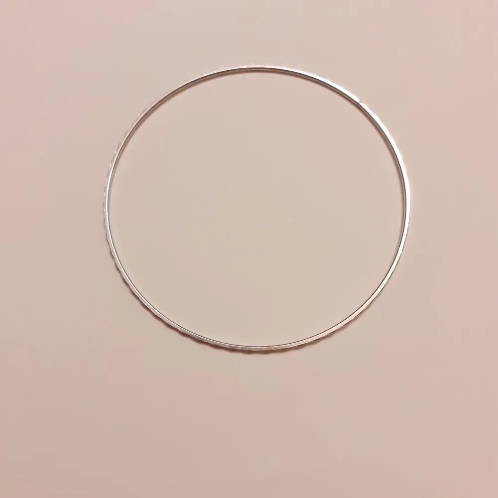 Silverarmband i nyskick. Armbandet är format som en ring och diametern är 6,5 cm . Accessoarer.
