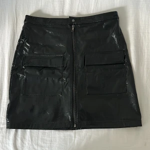 Skinn-liknande kjol  - Skinn-liknande kjol med dragkedja från NAKD. Väldigt snygg och i mycket fint skick, endast använd fåtal gånger. Storlek 38