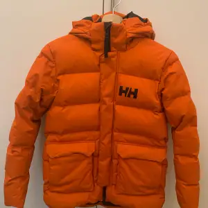 Helly Hansen Jacka Orange. Jätte bra skick. Nästan helt ny och ser ut som ny. Puffer jacka. Köpte från HellyHansen.se 