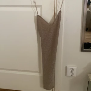 Glittrig Champagne färgad klänning  - Aldrig använd, öppen rygg, kan skicka fler bilder om de behövs! 
