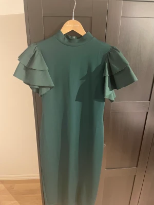 Fodral klänning strl m testad - Endast testad Grön fodral klänning Vadlång Volang armar Slits på baksidan  Dold dragkedja längs hela ryggen Djur och rökfri hem 