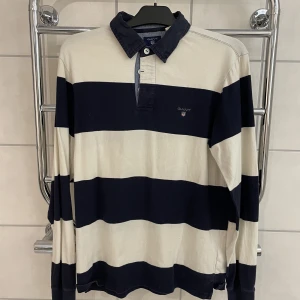 Långärmad randig piké gant - Långärmad pikétröja från Gant. Randig marinblå och vit. Använd men bra skick. Storlek M