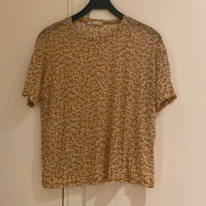 Blommig T-shirt  - Gul blommig T-shirt, lite transparent men inget som stör. 