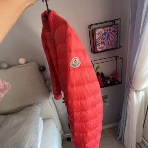 Moncler jacka - Sparsamt använd! En  unik korall/röd moncler jacka som är i en av de äldre modellerna. Säljer den då jag inte längre har användning för den.  Kvitto finns tyvärr inte då jag haft den ett tag och råkat tappa bort kvittot men jackan har en scanning kod.