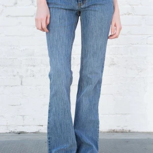 lågmidjade bootcut jeans - Ett par jättefina Brielle 90’s jeans från Brandy Melville. Säljer då de inte kommer till tillräckligt mycket användning. Inga defekter förutom att jag själv sytt in ett skosnöre vid midjan men det går enkelt att dra ut!❤️ nypris:500kr