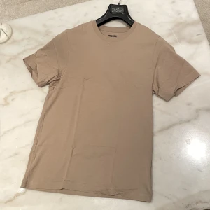 Beige tshirt - Fet tshirt till sommaren. Sitter bra på kroppen o skönt material. Stilren och fin beige färg. Passar till allt. Använd fåtal ggr (2-3 ggr), annars i nyskick.