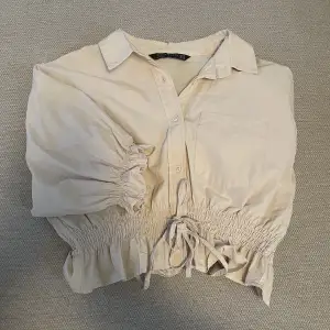 En beige croppad skjorta från DiLViN WOMAN.  Storlek 40 så motsvarar en M/L.   Nypris 299kr.  Köparen står för frakten, pris kan diskuteras.
