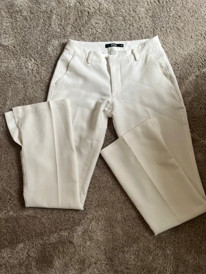 Lågmidjade kostymbyxor  - Vita lågmidjade kostymbyxor i storlek 36 från bikbok! Har en slita även vid benet!  Använda fåtal gånger så i väldigt bra skick! 😊