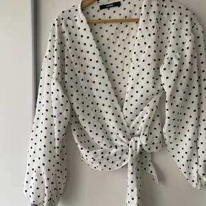 Prickig omlottopp från bikbok  - Prickig blus i omlottmodell. Oanvänd