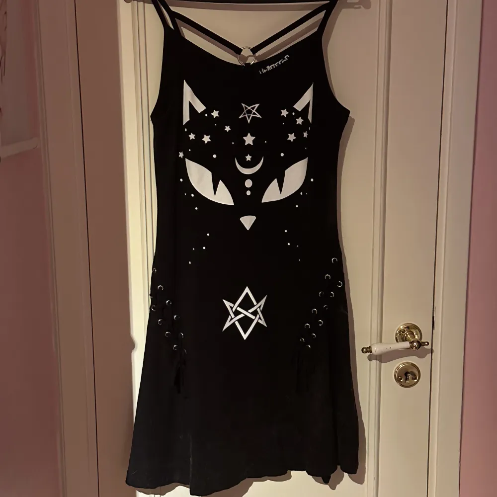 Jättefin mellanlång klänning av märket Heartless. Med tryck på en svart katt. Storlek S fint använt skick.  Katter finns i hemmet. Klänningar.