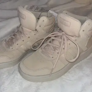 Säljer ett par helt oanvänd adidas Hoops 2.0 MID i en smutsrosa/Beige färg, kartong finns ej. 