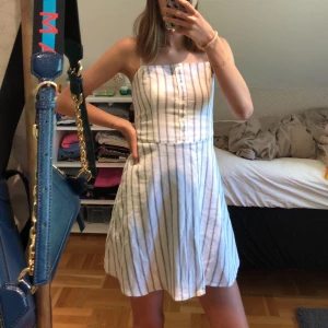 Vit randig klänning - Vit klänning med gråa ränder, knappar och smala band. Stretchig rygg (bild 3). Sparsamt använd och i fint skick!💞