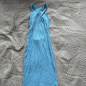 Super fin blå långklänning med criss cross i ryggen och slits bak på klänningen. Helt oanvänd! 