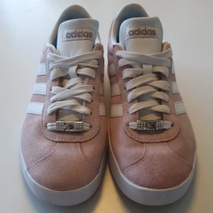 Adidassneakers rosa  - Rosa Adidassneakers strl 40  Mycket bra skick. Har satt dit lite "glitter" på skösnörena, vilket går att ta av om så önskas. Pris 250kr  Nypris 699kr 