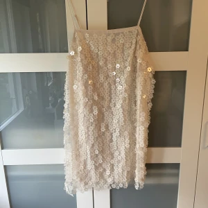 Ljus paljettklänning - MAGISK klänning med paljetter i blomform! Är i en ljusvit/beige färg, tycker färgen gör sig mer rättvisa på bild 2!! Mycket fint skick! Perfekt till fest!  3 FÖR 2 på min sida!!