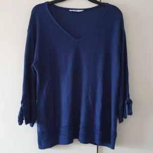 Stickad tröja  - Blå stickad tröja lite längre än trekvartsärm helt i nyskick/oanvänd rosetter å slitz vid ärmslut , V-ringad  Strl 38/40 Pris 180kr 