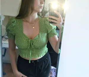 Grön blus  - Grön prickig top. Tunt material vilket är skönt till sommarn. En Crop top med puffärmar, knytning vid brösten