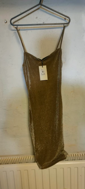 Festklänning - Helt ny festklänning säljes.  Guld/glitter Nypriset 399:-