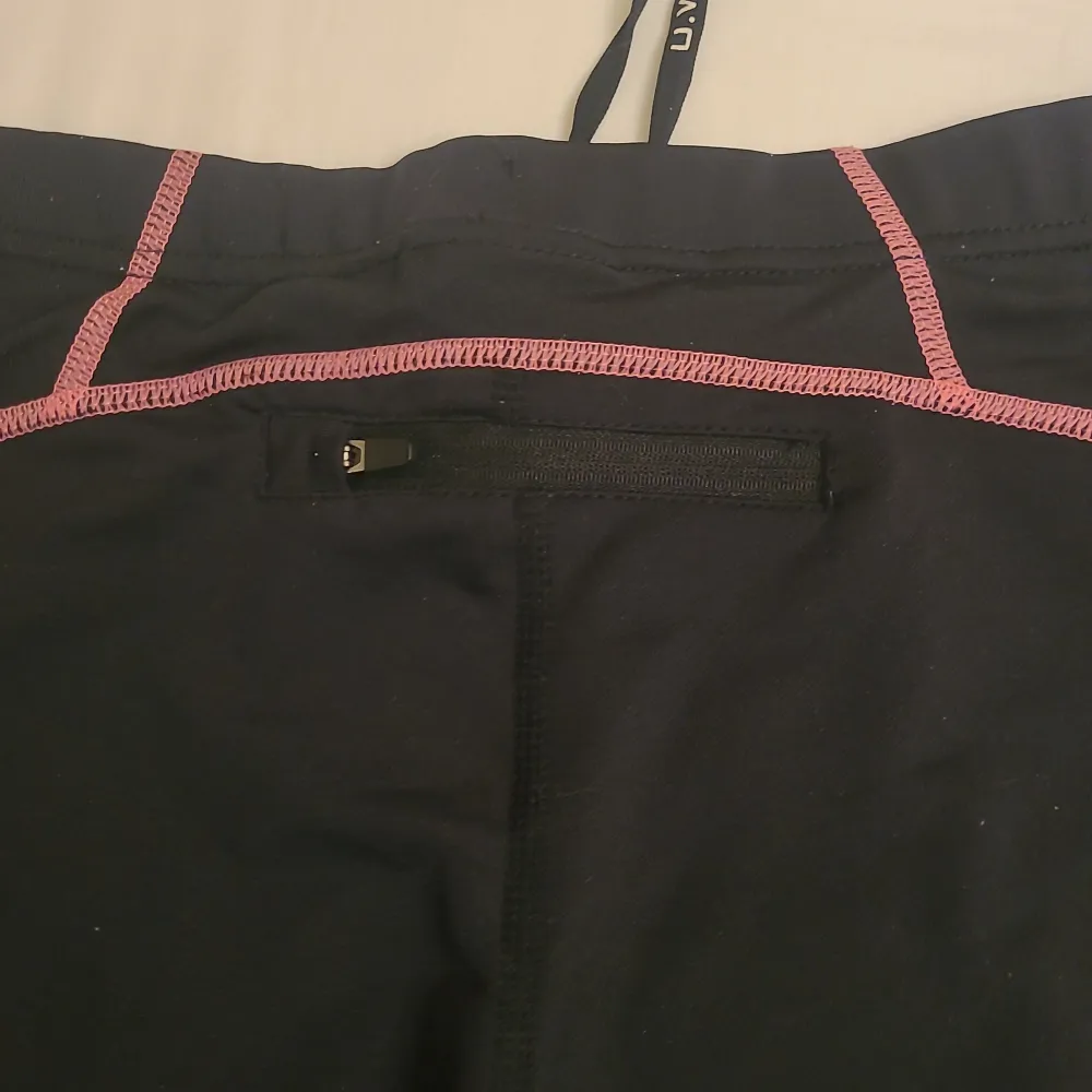 Helt nya träningsbyxor med rosa detaljer och knytning i midjan. Ficka med blixtlås på baksidan. . Jeans & Byxor.