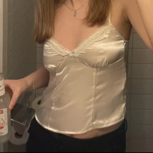 satintopp med spets - jag säljer denna oanvända satintopp med spets som endast är provad. har en dragkedja på sidan som gör den enklare att sätta på sig. rekommenderas för någon med lite mindre bröst då toppen är lite tajtare vid bysten🫶🏼 slutsåld på hemsidan