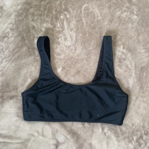 Svart bikiniöverdel - Svart bikiniöverdel med en liten vit fläck som går bort i tvätten (plaggen skickas alltid nytvättade). Den är stretchig och bekväm och håller allting på plats när man badar eller solar. 