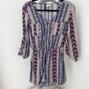 Kort Byxdress H&M - Säljer denna snygga byxdress från H&M Divided. Använd Max 5ggr. Resår i midjan och knappar upptill samt två bröstfickor.