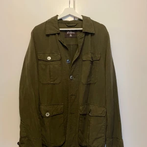 Oscar Jacobson safari overshirt i mörkgrön i storlek L - En Oscar Jacobson safari overshirt i storlek L i nyskick, inköpt för ca 6 månader sedan använd 1 gång pga fel storlek, nypris ligger på 2500kr