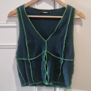 Topp med sömmar  - Fin cool mörkgrön topp med neonfärgade sömmar. Knappt använd, fint skick.