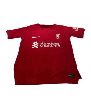 Liverpool - En Liverpool tröja i storlek s som är röd. Den är perfekt passande och av hög kvalitet. Dess andningsförmåga gör den idealisk för både matcher och träning.