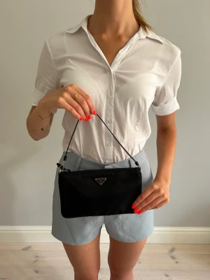 Prada re-nylon miniväska - Utmärkt skick. Elegant. Garanterar äkthet (pengarna tillbaka annars). Äkthetskort följer med.  Fler foro , info och andra väskor ur min kollektion —> Pretti.se