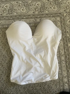 Vit Korsett topp - jättefin och skön korsett topp, säljer då den är för liten för mig. Baksidan har knäppen i tre olika storlekar, passar nog bäst på en XS/S. Den har en liten fläck på baksidan, går att se på andra bilden. Saknar även band. 