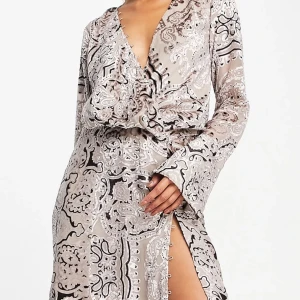 Paisleymönstrad sammetsklänning med omlottdesign och öppen rygg - Oanvänd med lappar kvar. Säljer eftersom passformen inte alls var den rätta på min kropp.  Långärmad miniklänning i glansig sammet med mönster. Lila/grå/rosa i färgen. Superfin på eätt person! 🤗