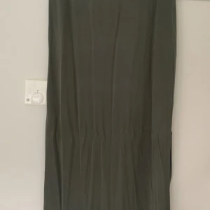 Kjol från VILA - Olivgrön kjol från Vila. Storlek L. Resår i midjan och strechigt material.  Längd ca 93 cm. En slits på ca 35 cm på ena sidan.