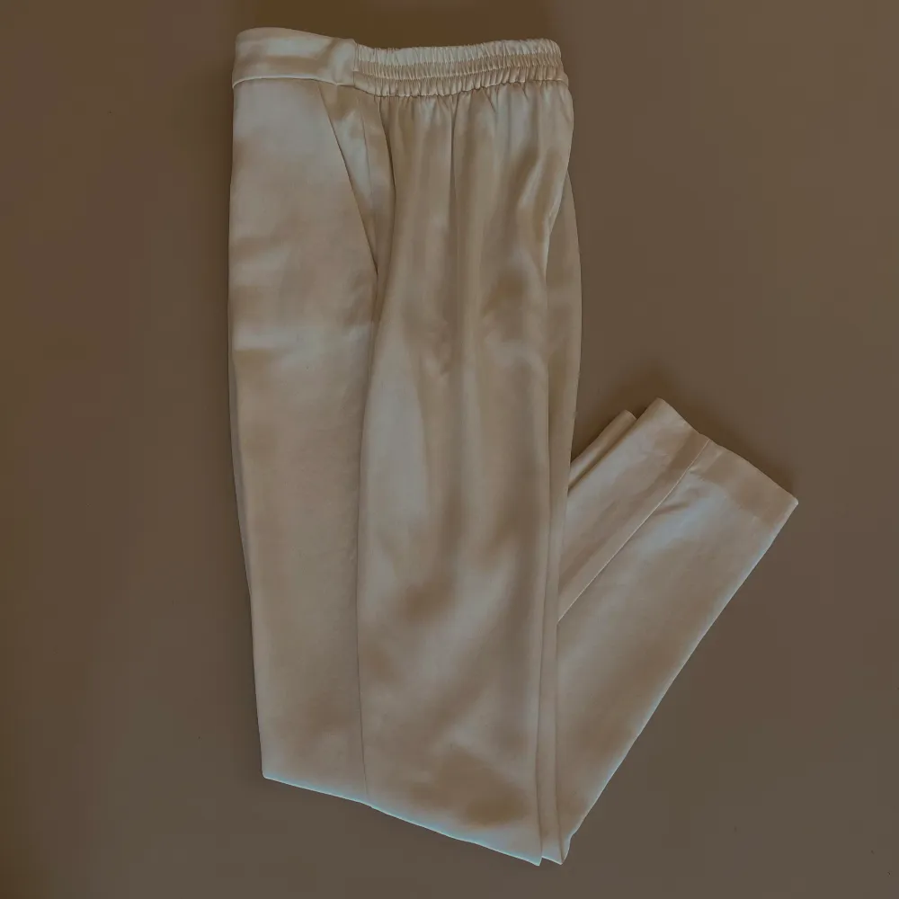 Silk Pleated Front Dress Pant with 2 Pockets. Tapered leg for slimming effect. Elastic waistband.   Waist to inseam is 26CM. Made with Deadstock Designer Silk Fabric. Excellent Condition.  92 CM Length 64 CM Waist 80 CM Hips 66 CM Inseam. Jeans & Byxor.