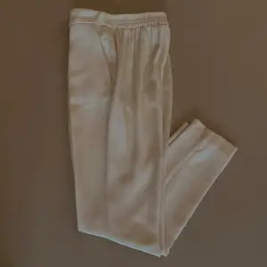 Silk Pleated Front Dress Pant with 2 Pockets. Tapered leg for slimming effect. Elastic waistband.   Waist to inseam is 26CM. Made with Deadstock Designer Silk Fabric. Excellent Condition.  92 CM Length 64 CM Waist 80 CM Hips 66 CM Inseam