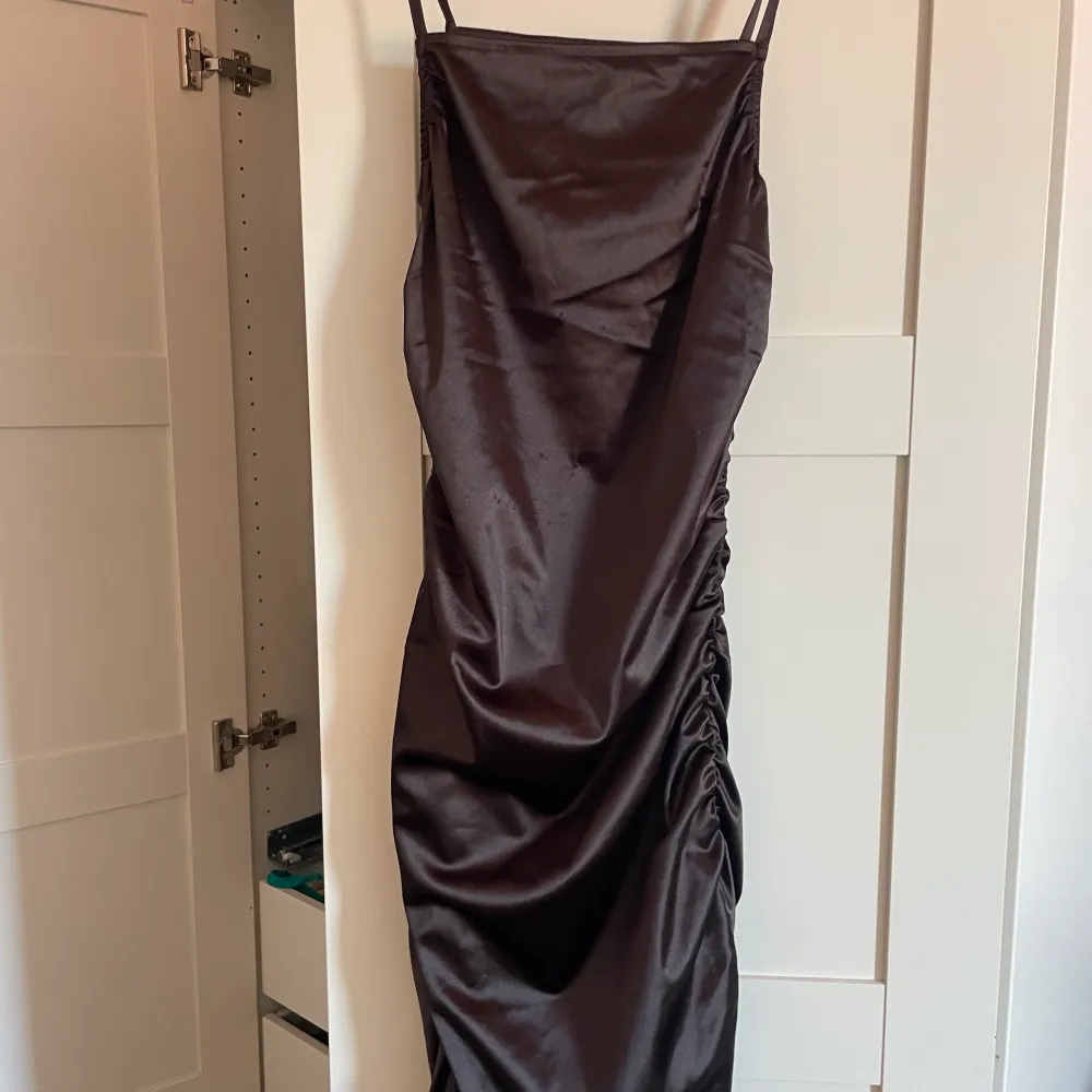 Snygg mörkbrun tight klänning i glansigt material! Aldrig använd med lapparna kvar🫶🏼. Klänningar.