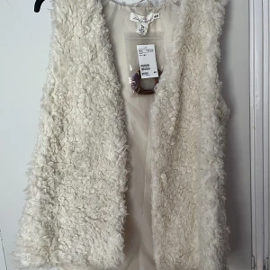 Väst - Oanvänd med prislappar. Cremefärgad med brunt läderband. 