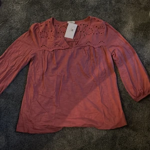 Trekvartsärmad blus - Säljer denna rosa trekvartsärmade blusen då den var lite för stor och kommer inte till användning. Den är i superbra skick med prislappen kvar. Den har broderi och är v-ringad. Skriv för fler bilder eller om ni har frågor💕✨
