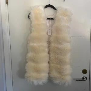 Fejkpäls väst - En vit väst. Helt oanvänd (alltså väldigt fluffig och fin), även prislapp kvar. Finns även fickor.