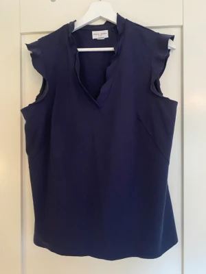 Söt kortärmad mörkblå blus  - Fin blus/linne från Holly & White med volang i halsen. 