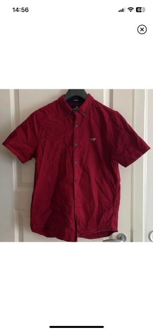 vinröd hollister skjorta stl M - Säljer denna fina skjortan ifrån hollister, kortärmad aldrig arnvänd, ny pris 350kr, kontakta mig kring frågor