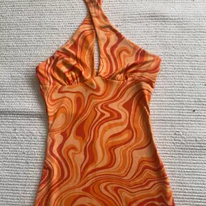 Orange klänning perfekt till sommaren och semester. Storlek XS. Går att både ha knuten där fram som på bilden eller ha den som vanligt. Endast använd en gång så precis som ny!💛 Köparen står för frakt!