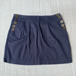 Mini kjol - Kort marinblå kjol med knappar på sidorna. Midjemåttet är 74cm💙