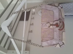 Guess väska med blank kedja - Jättefin Guessväska med tung blank kedja. Finns ficka med dragkedja i väskan och även fler utan dragkedja och även bak på utsidan med dragkedja. Guess fantasi mönster på canvasen. Ingår jättefin Guess pappersväska med handtag.