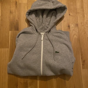 Lacoste zip hoodie - Säljer min Lacoste zip hoodie då den inte kommer till användning, den är nästan helt ny använd fåtal gånger, vid funderingar är det bara att skriva till mig 