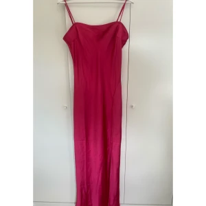 Rosa satinklänning - (Skrikig) rosa satinklänning. Slits i ena sidan och justerbara ärmar. Storlek L. Aldrig använd.