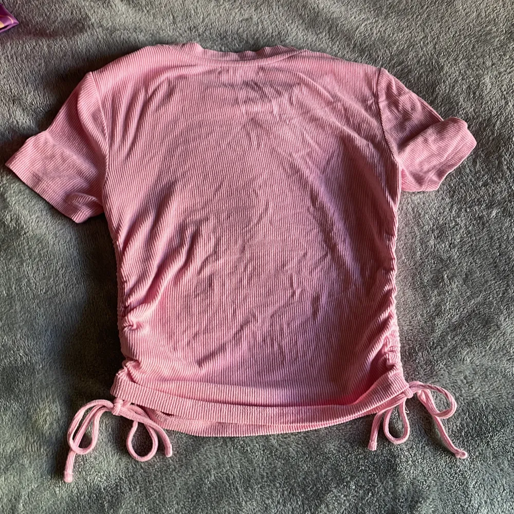 En rosa T-shirt som har knyten på sidan. Passar med mycket och har väldigt stretchigt och mjukt👍. T-shirts.