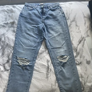 Mid-Rise jeans med hål från Gina - Säljer ett par Jeans med hål från Gina!  Jag skulle säga att det är baggy jeans och rätt så raka nertill.  Innerbenet är 70cm, midjan är 69cm, Använt 1 gång, så väldigt bra skick. Priset kan diskuteras, nypris: 499kr 