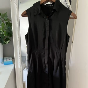 Klänning - Svart klänning i tunnt material som faller så fint. Knappar hela vägen så man kan knäppa hur man vill.