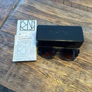 Chimi solglasögon  - Ett par jättefräsch bruna somriga chimi solglasögon.  Kom tyvärr inte till så mycket användning och är därför nästan som nya. Köpta på NK Göteborg för 1500 kr nypris. Kvitto och låda finns med. Passar både killar och tjejer. 